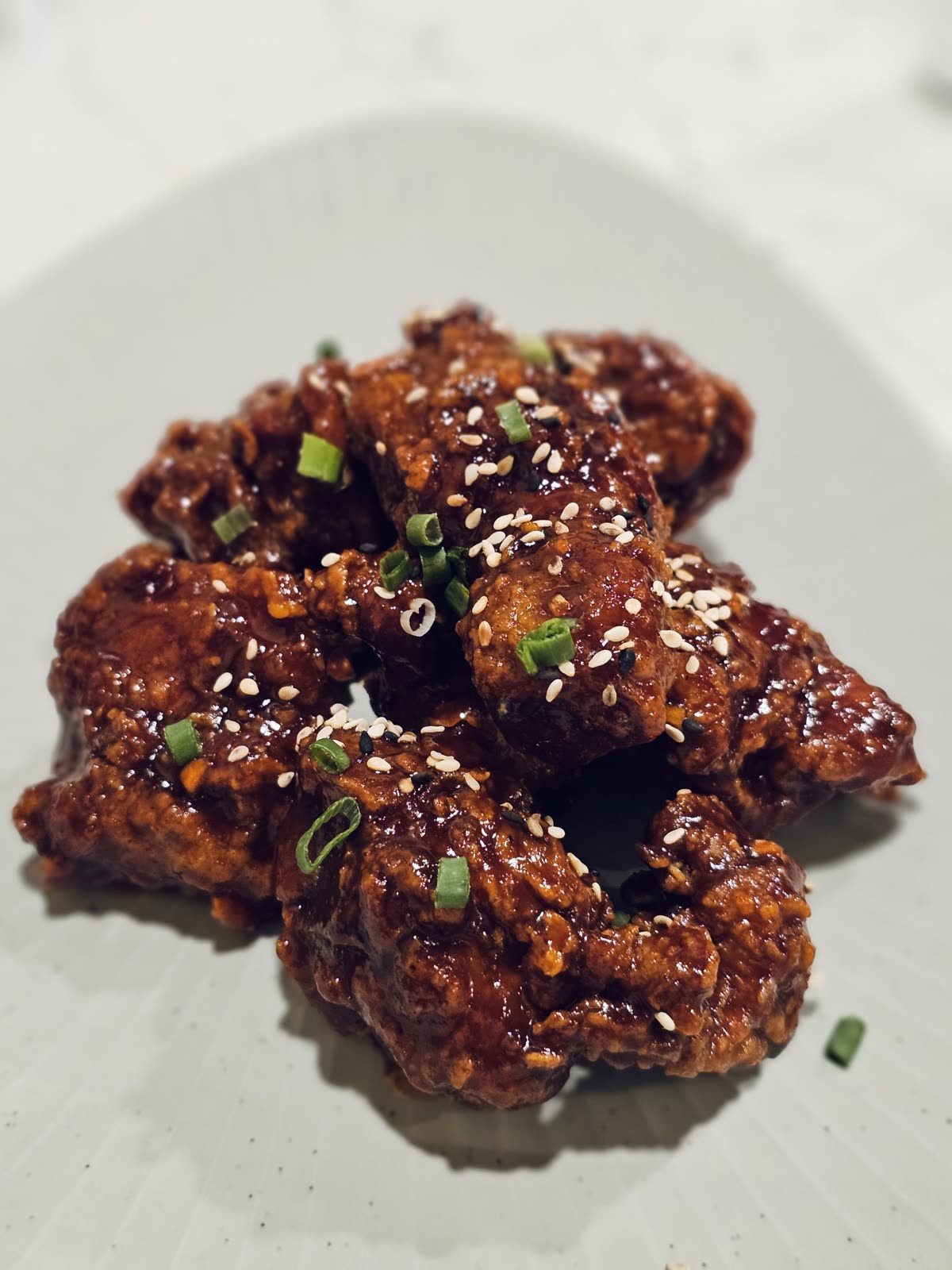 Crispy Korean fried chicken pieces coated in a rich, glossy sauce and topped with sesame seeds in Kozhikode, Kerala, look hot, spicy, and appetising. — Yangnyeom vs Ganjang: Which One Is Less Spicy?