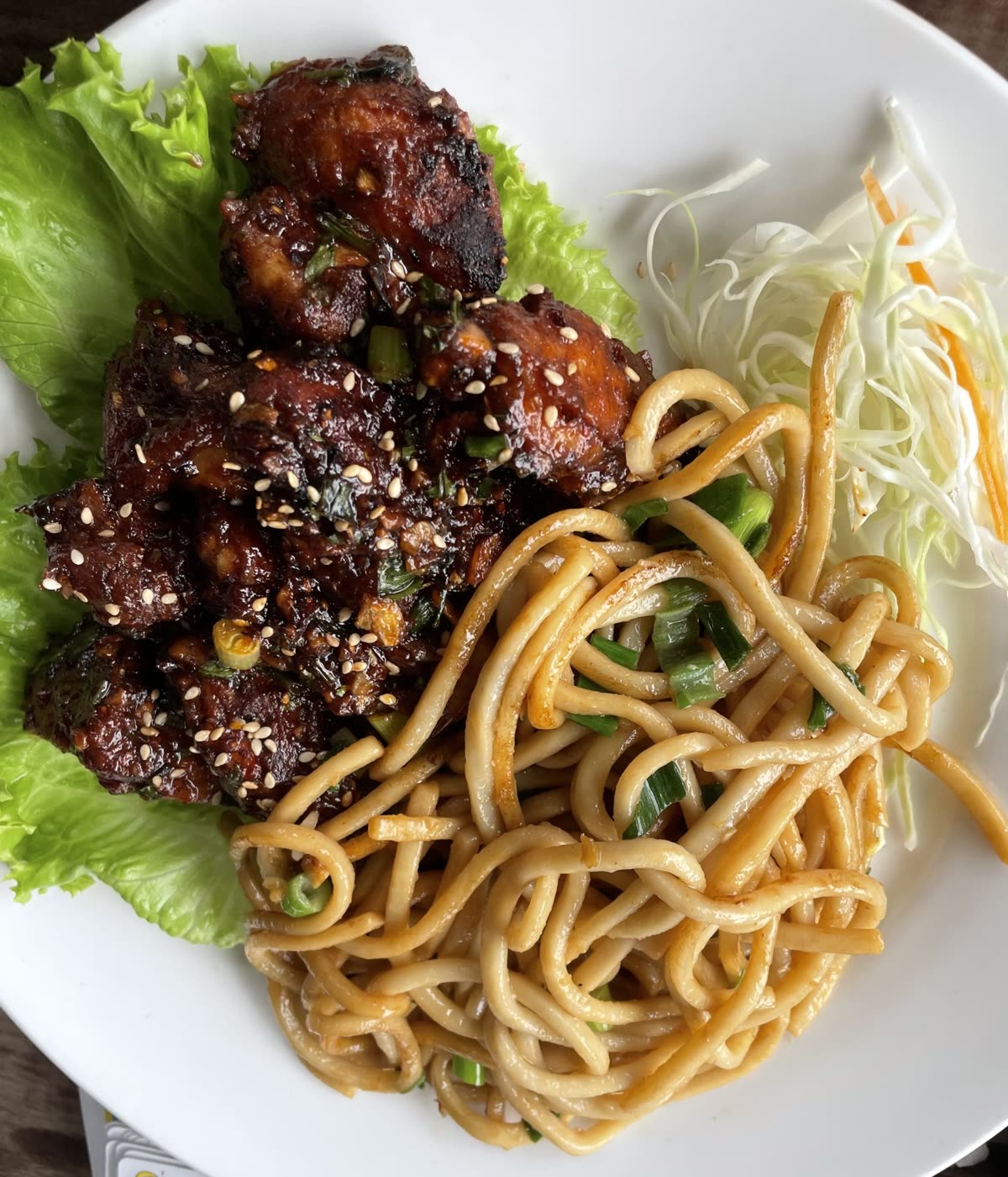 Top-down close-up of a meal on a white plate with stir-fried noodles, glazed chicken topped with sesame seeds on lettuce, and shredded cabbage on the side. — When to Glaze the Chicken: Last 5 Minutes Only