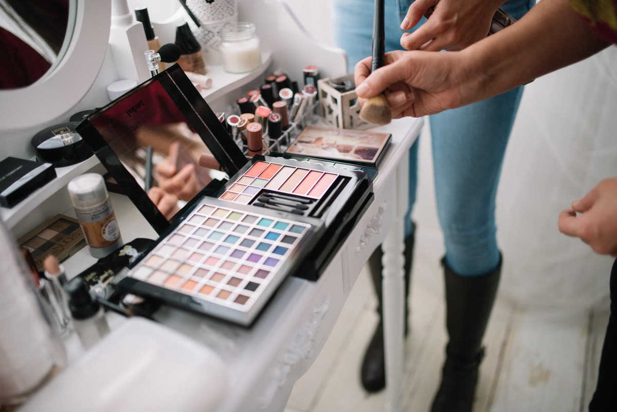 Hands of a makeup artist are shown holding a brush while colorful makeup palettes are arranged neatly on a clean table in a well-lit studio, highlighting creativity and artistry — espoir Aute Latte palette — the revival everyone watched