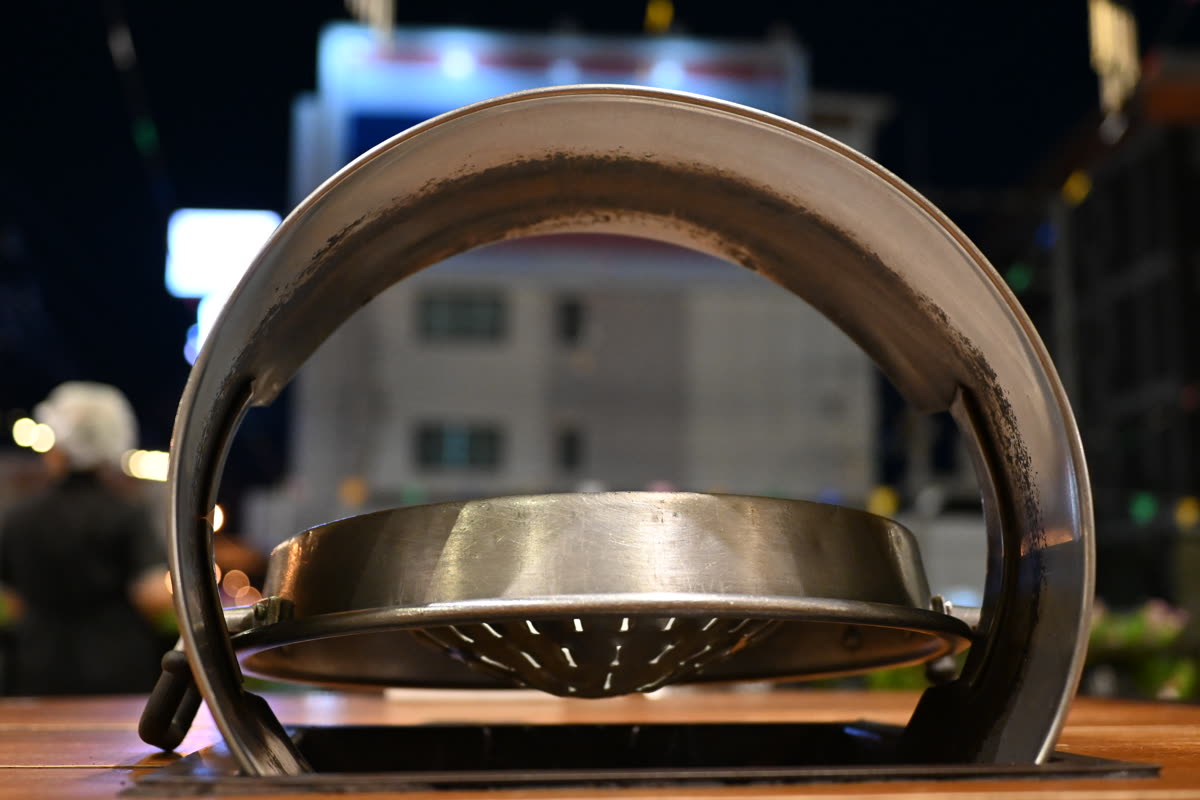 DZ3 0614 Close-up of a tabletop charcoal grill set into a wooden table ready for a night of grilling with blurred street lights in the background — What Korean food do Japanese people eat?