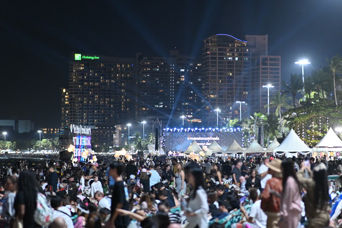 DFC 3794 Thousands gather on a beachfront at night for a large outdoor concert or festival with a brightly lit stage tents and city high-rises glowing in the background — BTS World Tour 2026 2027 Dates And Cities At A Glance