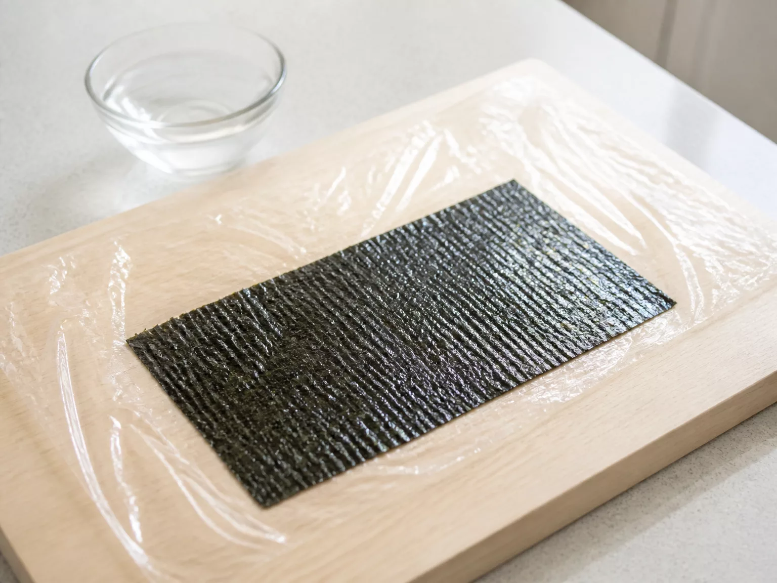 Step 1: Lay one half sheet of gim shiny-side down on a dry board or a sheet…
